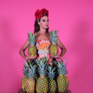 Molotov Jukebox, a lady stands behind a pile of Pineapples